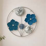 Decorative wall art with blue flowers and metallic elements on a plain wall.