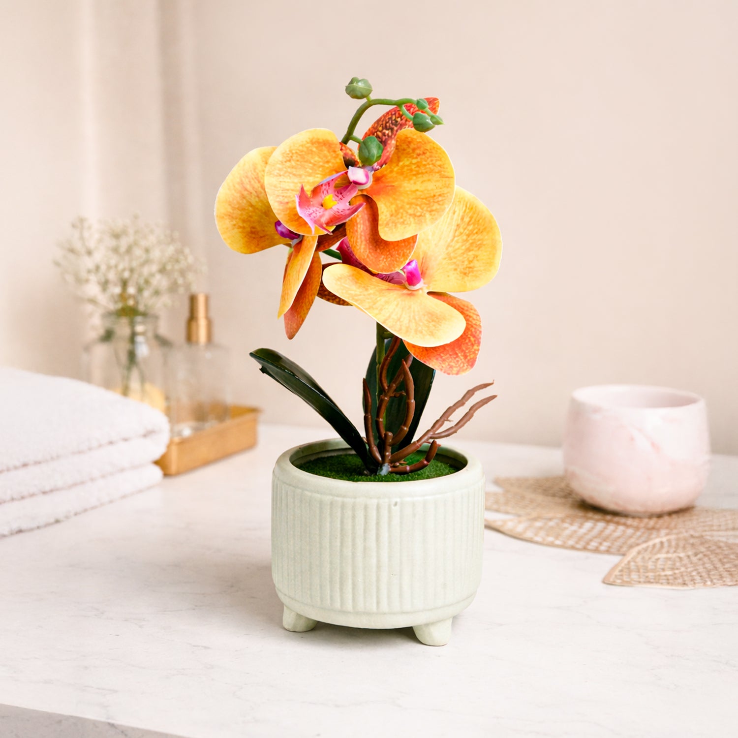 Artificial orchid plant in a white pot on a table with a neutral background